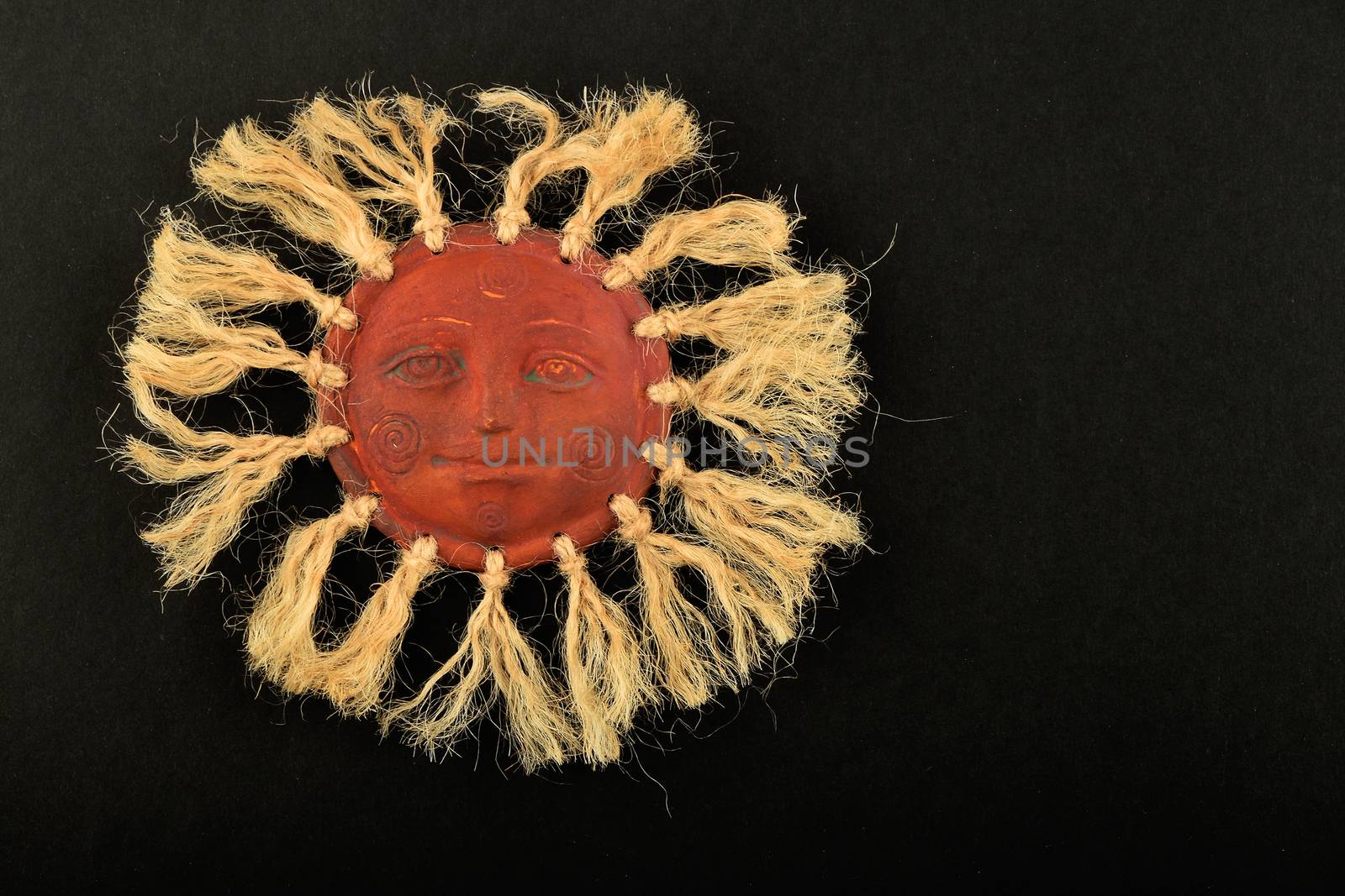 Mexican traditional ceramic happy sun face symbol plate with rays of jute rope isolated on black