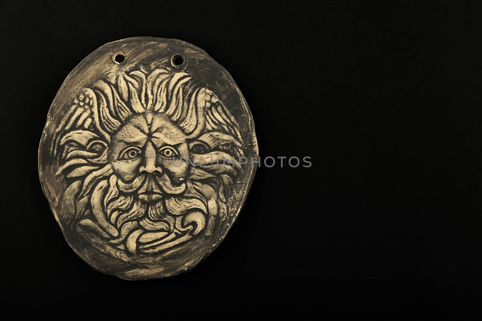 Tourist ceramic souvenir replica of male Gorgon Medusa head in Minerva temple in Roman Bath in England isolated on black