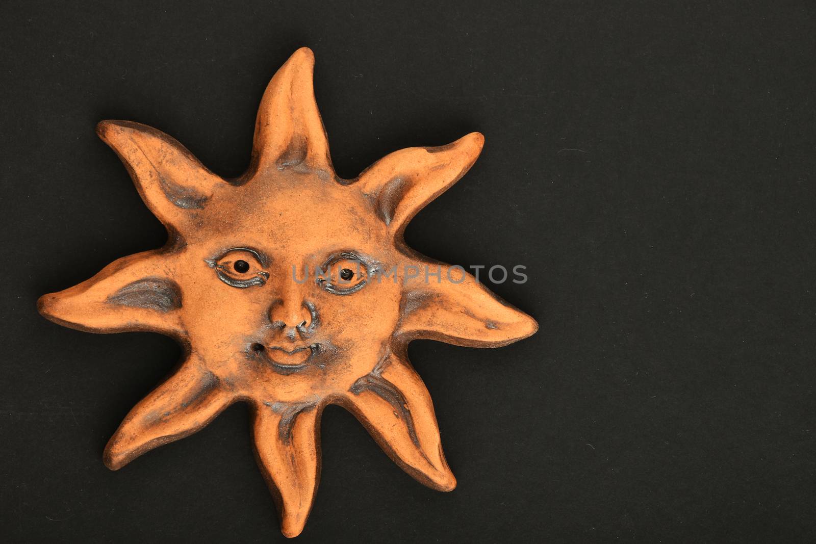 Smiling glazed ceramic sun happy face souvenir isolated on black