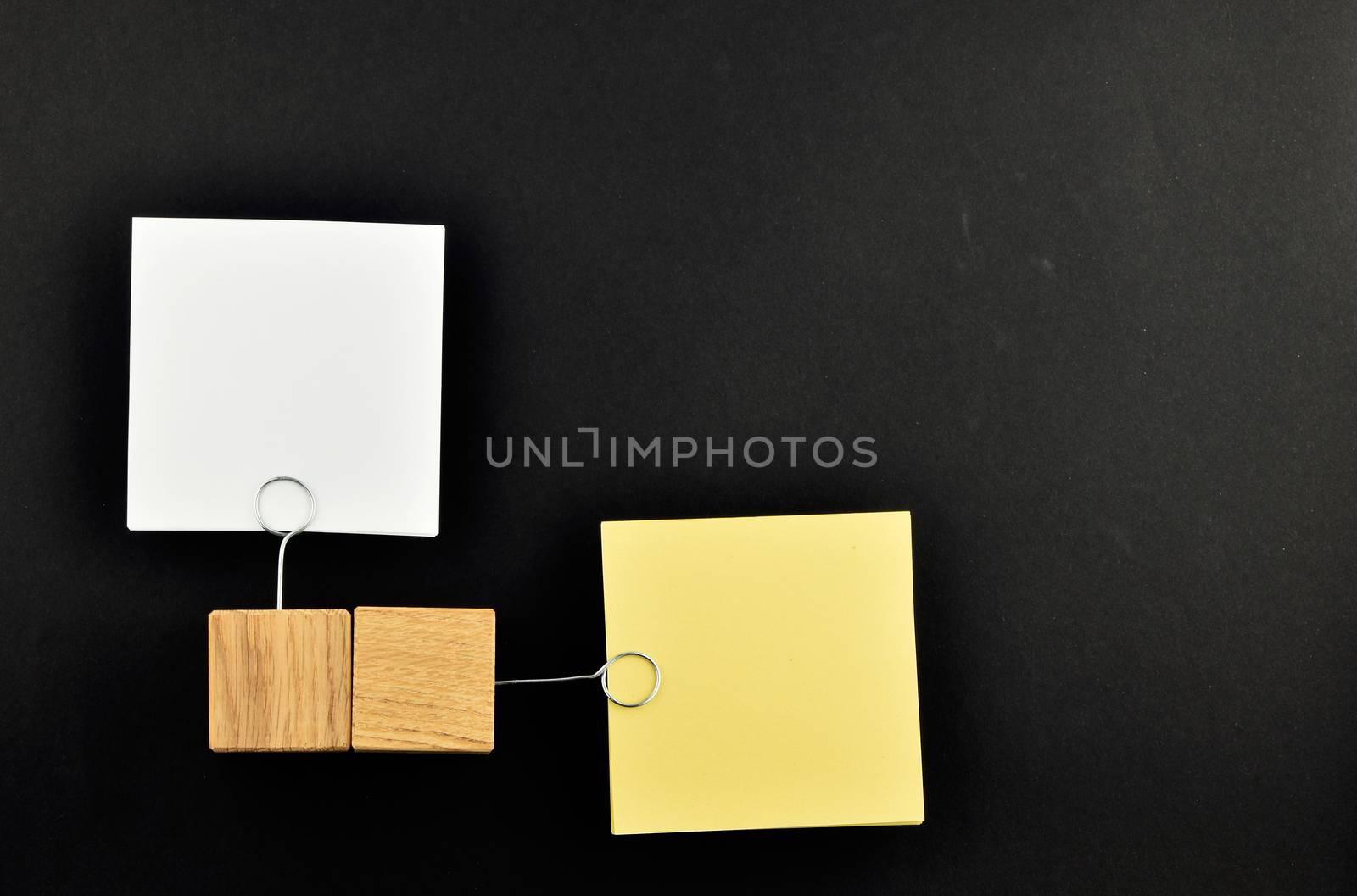 Opposite Opinion - Two paper notes, white & yellow,  with wooden holders in different directions isolated on black paper background for presentation