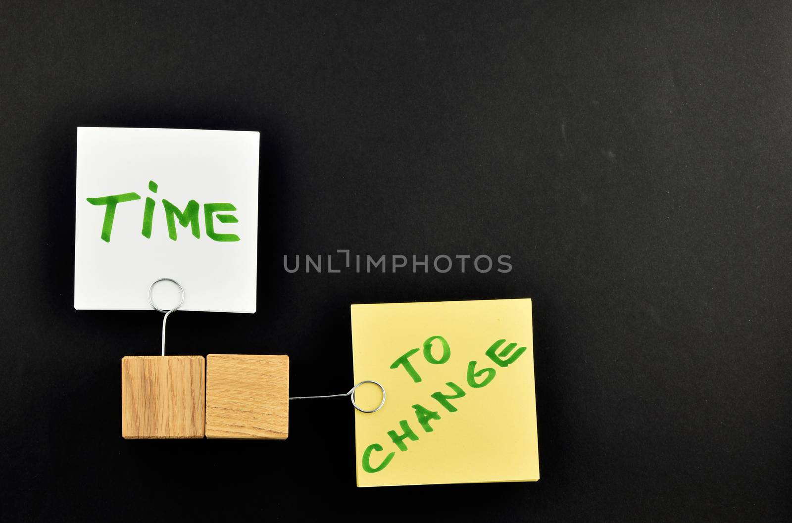 Time to change,  Two paper notes, white & yellow,  with wooden holders in different directions isolated on black paper background for presentation