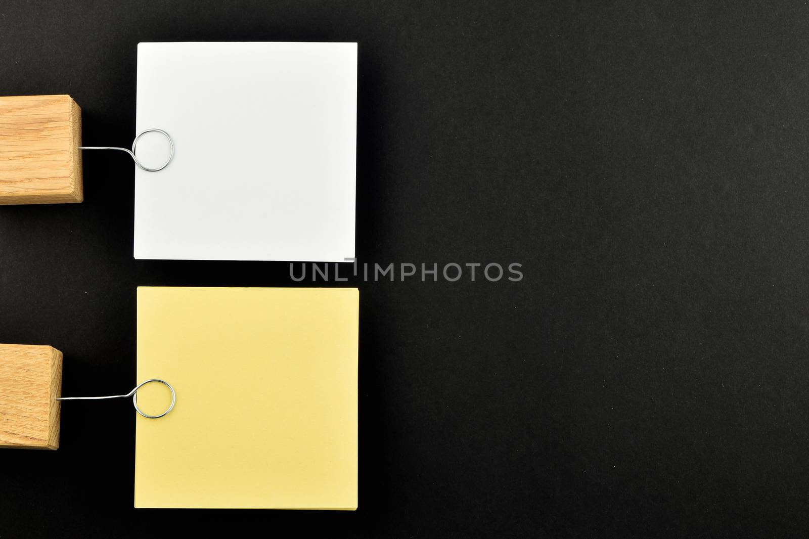 List, Two paper notes, white and yellow, with wooden holders isolated on black paper background for presentation