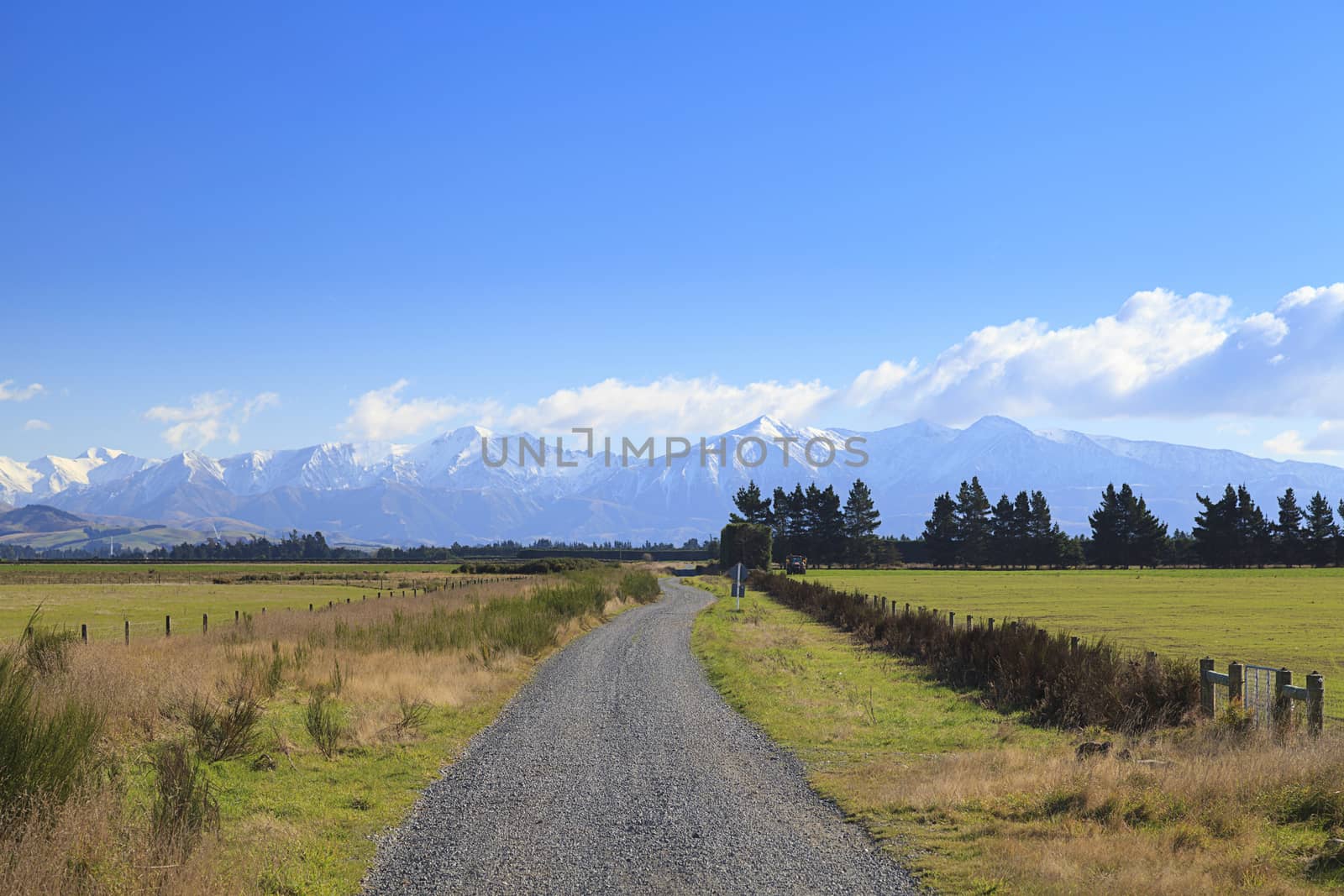 Straight rural gravel road to mountains of the Southern Alps, South Island, New Zealand.
