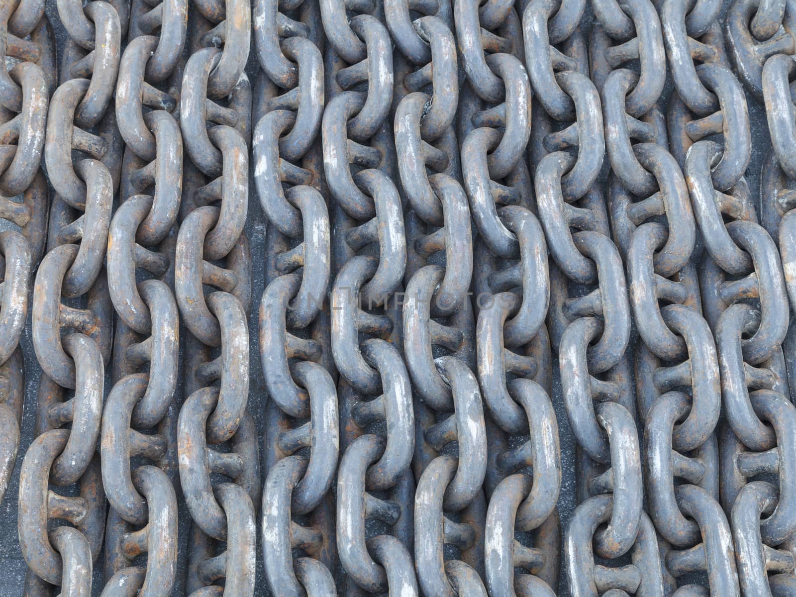 Many lines of used rusty heavy iron chain on the ground.