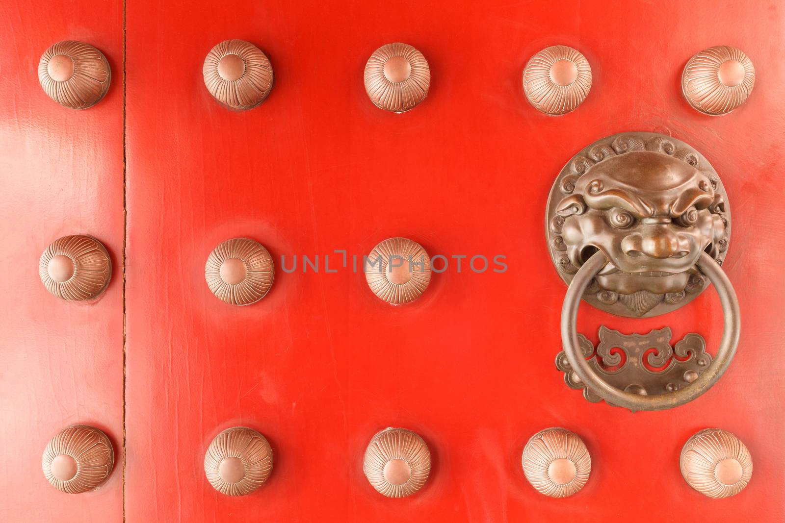 Chinese lion face door knob on the red gate of buddhist temple in Singapore.