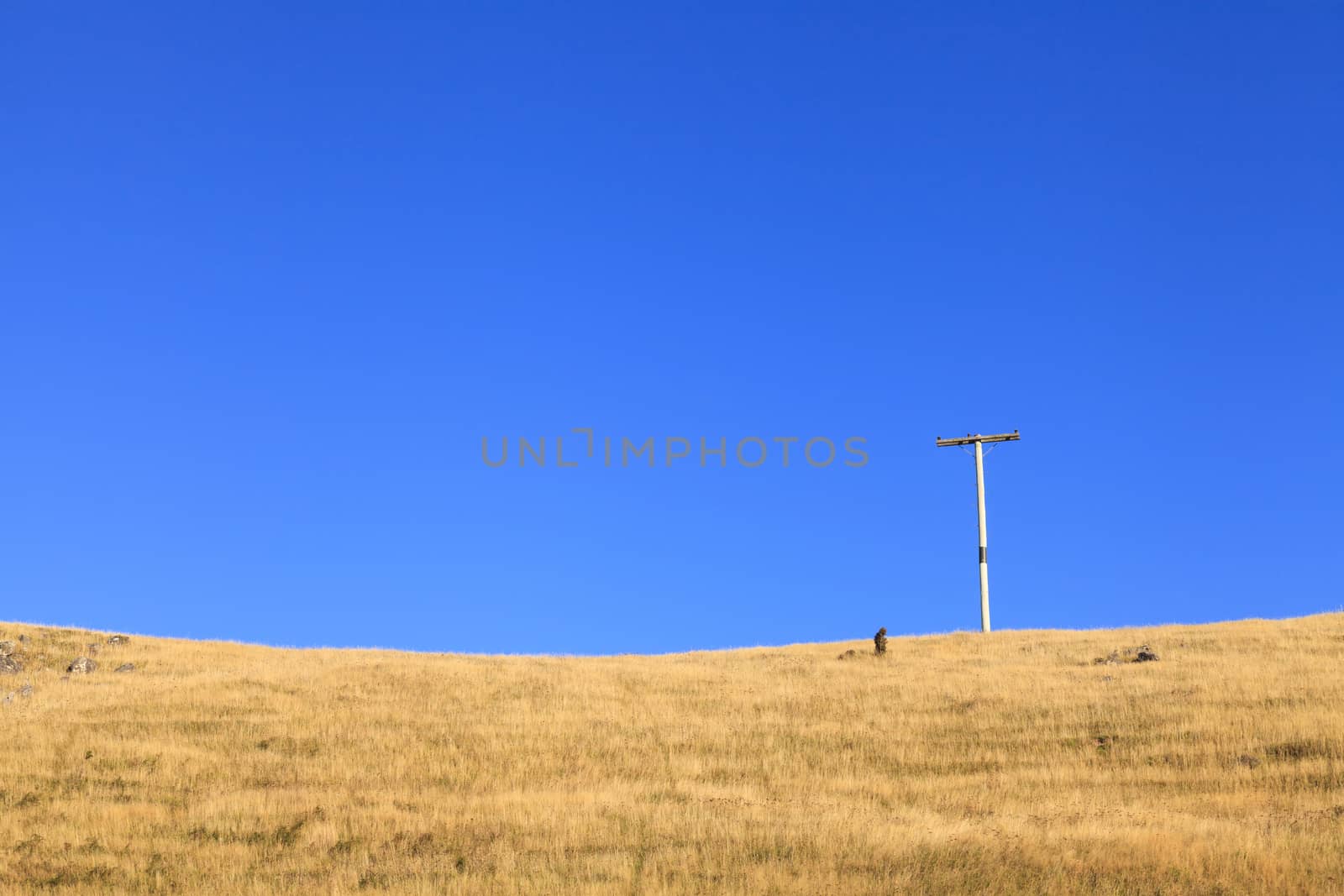 Lonely Electricity post stand alone over dry glass field.