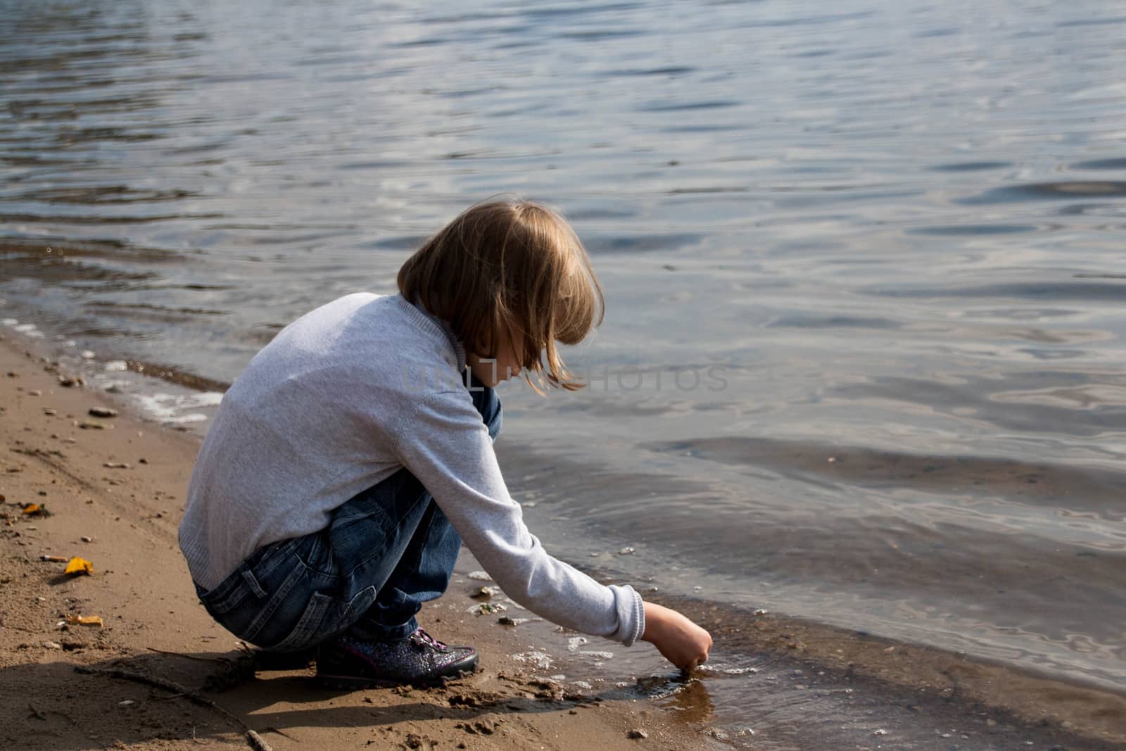girl draws in the sand on the river Bank
