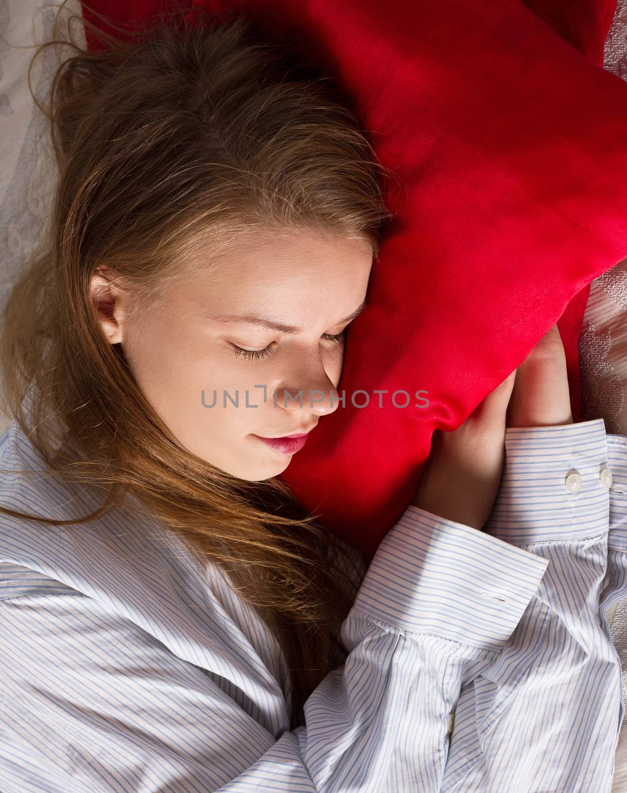 Beautiful woman is sleeping on red pillow. Pretty girl on the couch.