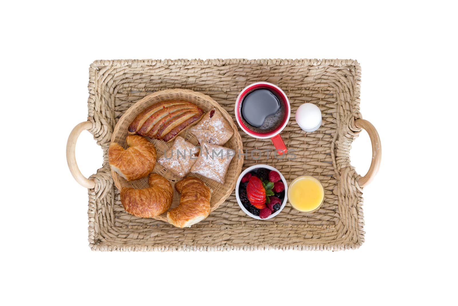 High Angle View of Wicker Breakfast Tray with Assortment of Breads and Berries, Coffee, Juice and Hard Boiled Egg on White Background