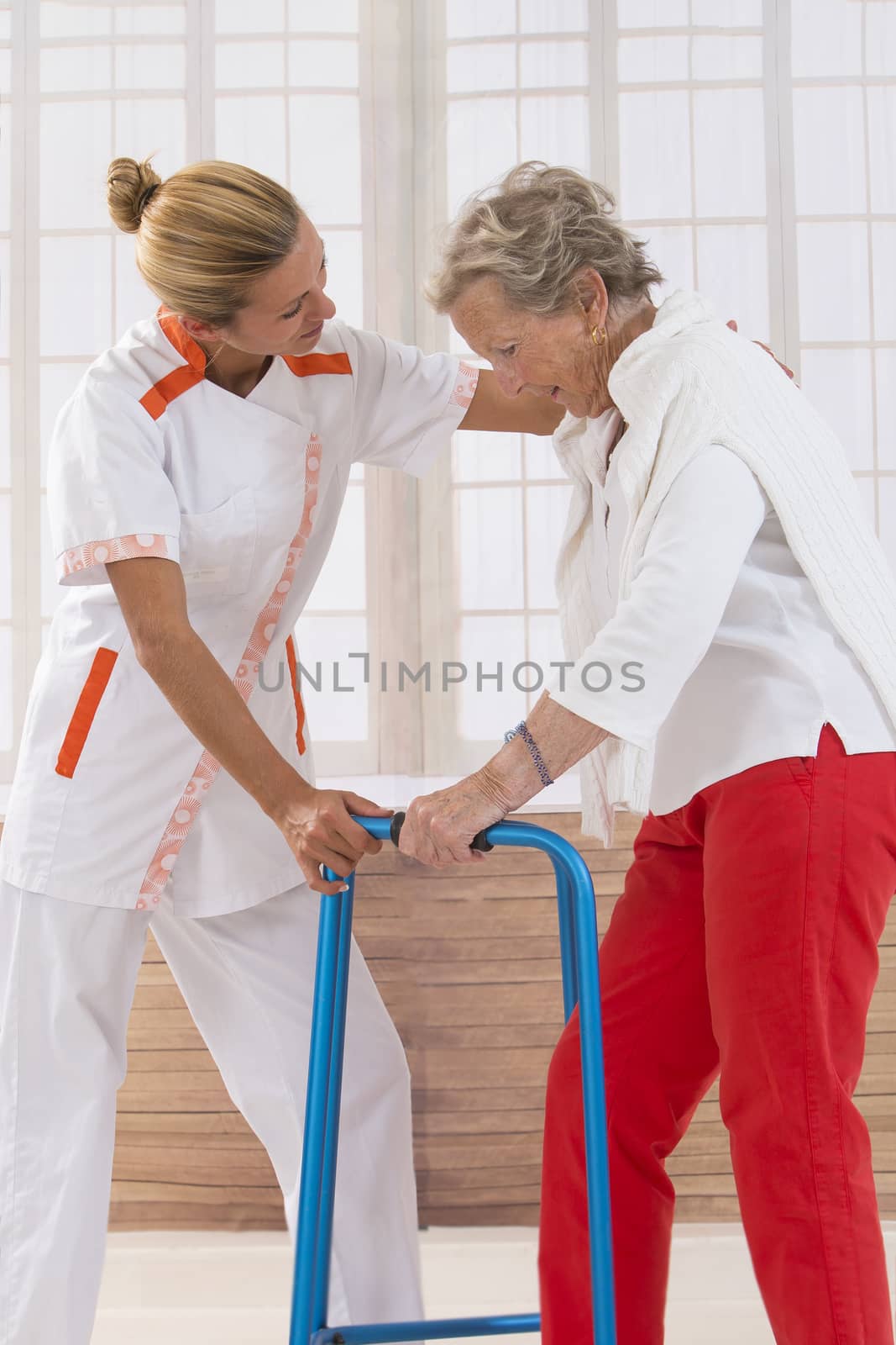 Care giver helping elderly woman to walk with a walker