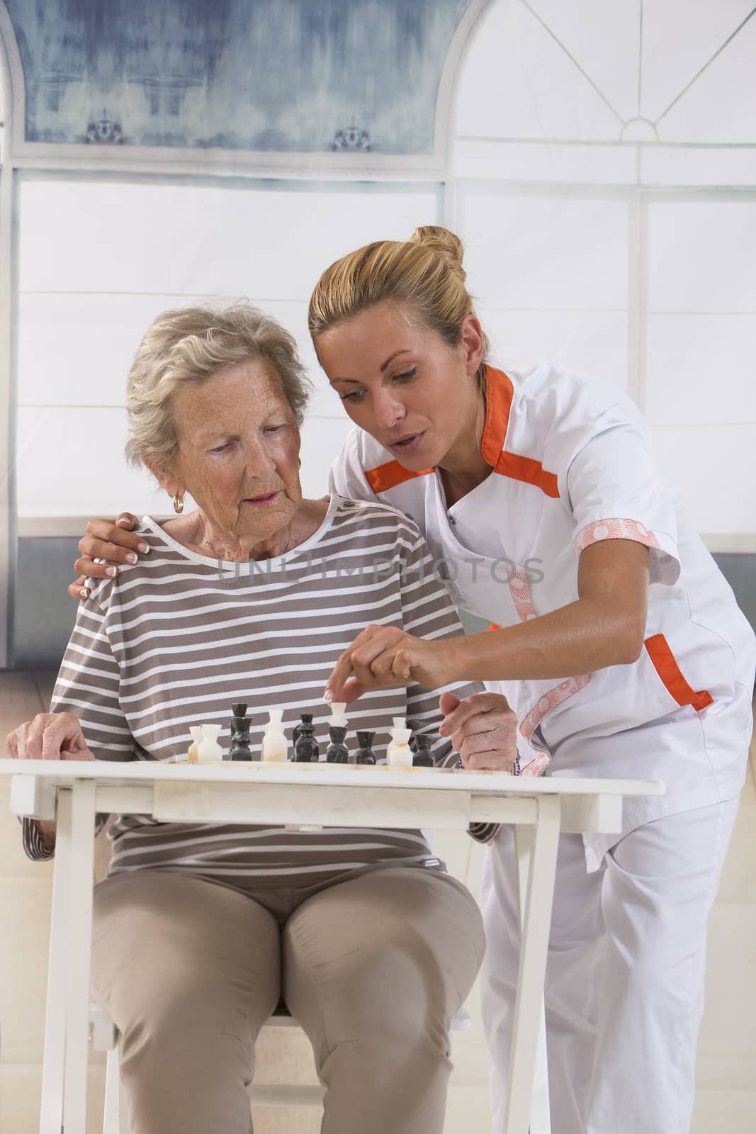 Senior woman playing with  nurse in retirement home by JPC-PROD