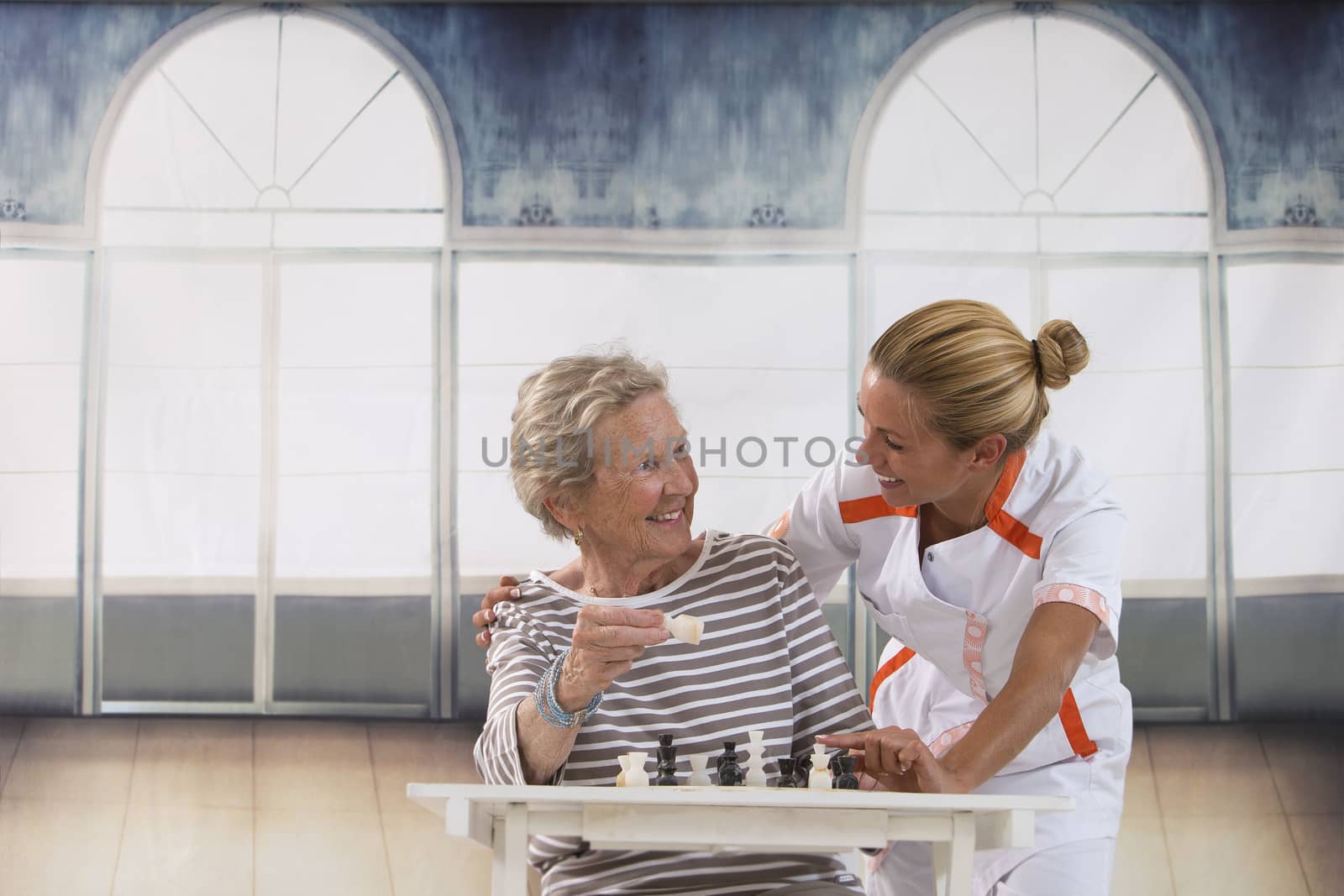 Senior woman playing with  nurse in retirement home by JPC-PROD