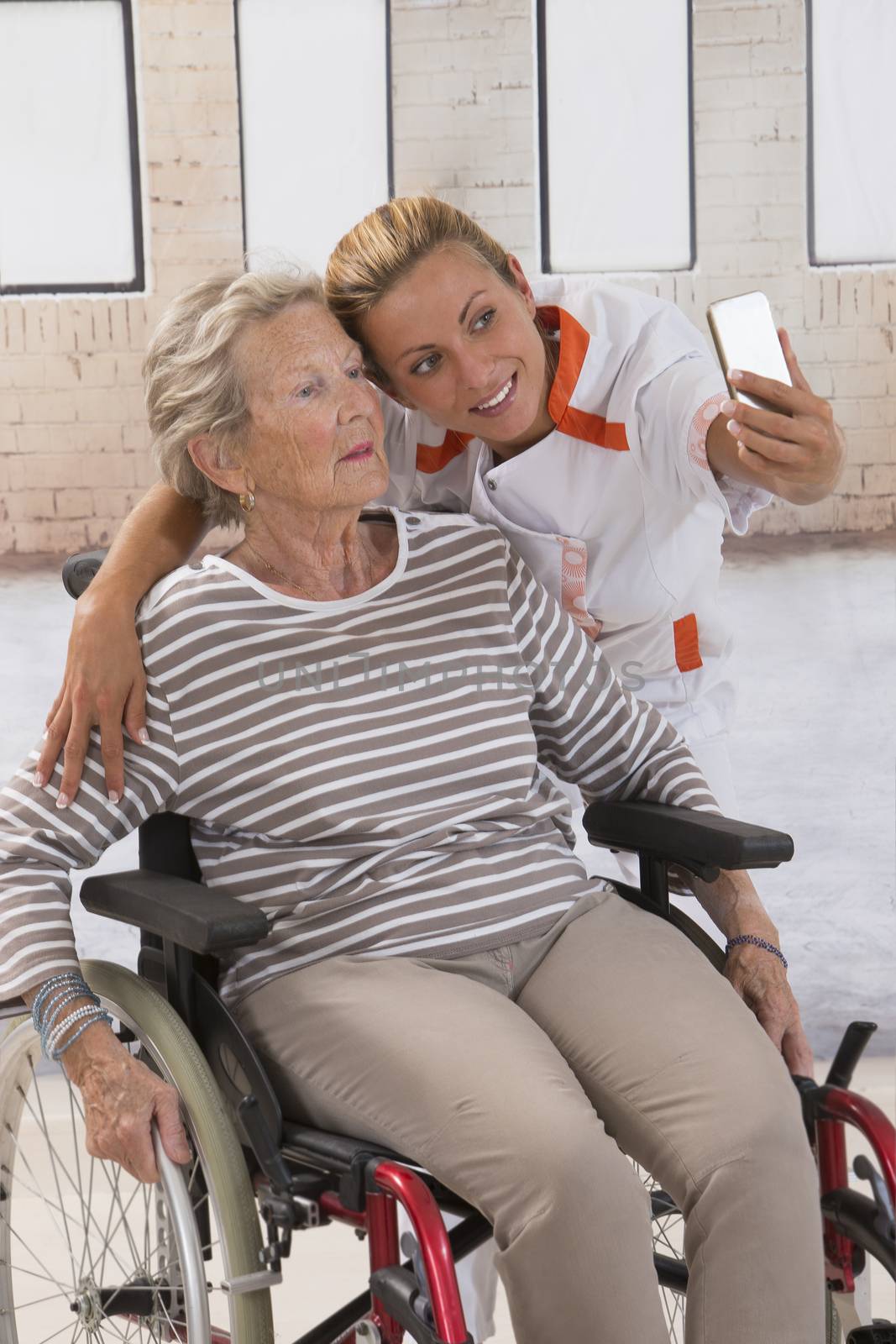 Young nurse taking a selfie to ensure the family about the good condition of the grandmother.