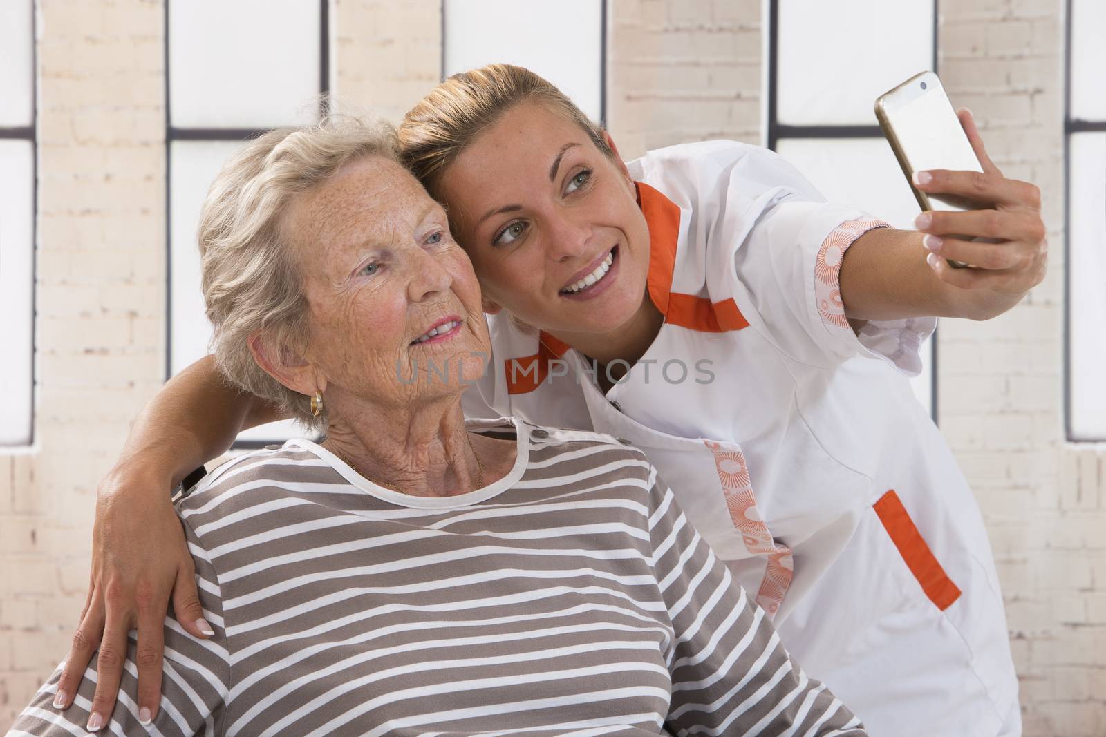 Young nurse taking a selfie to ensure the family about the good condition of the grandmother.