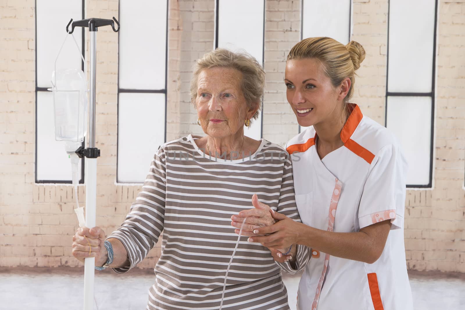 Nurse walking next to a patient with IV drip in hospital coridor