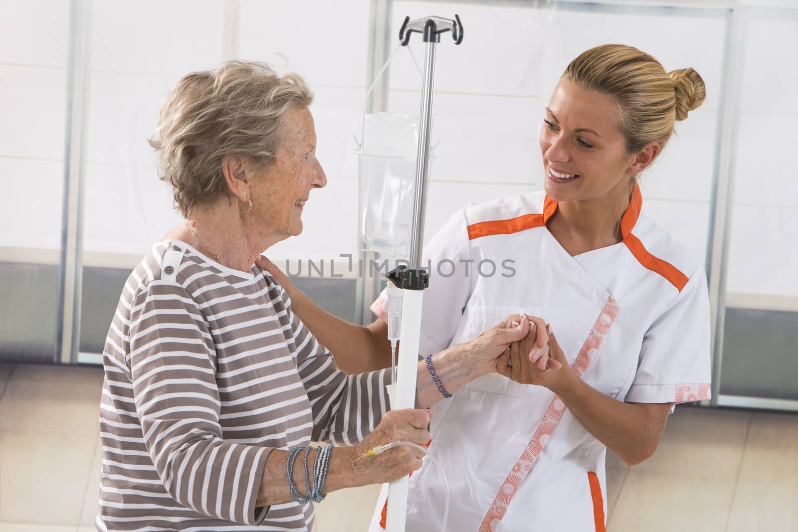 Nurse walking next to a patient with IV drip by JPC-PROD