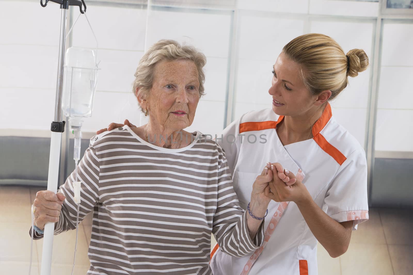 Nurse walking next to a patient with IV drip by JPC-PROD