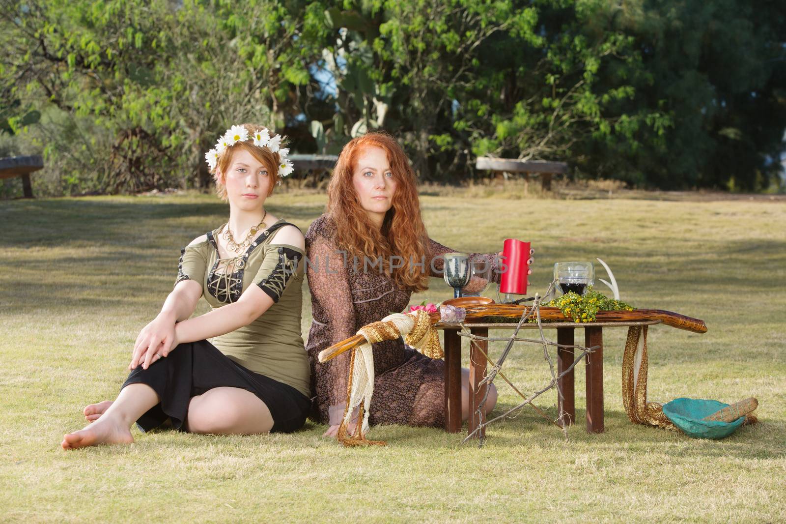 Two serious pagan females sitting at altar with pentagram