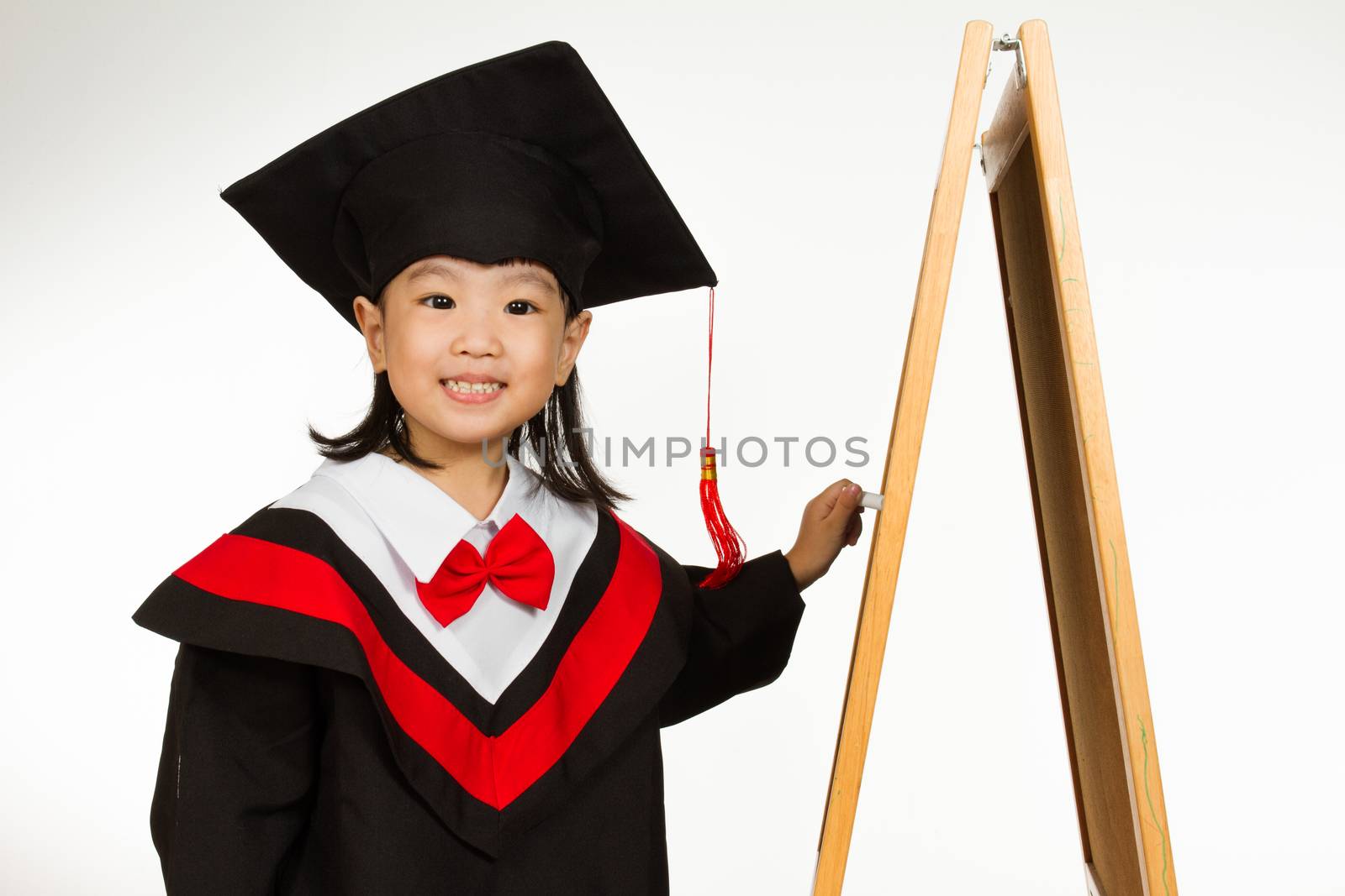 Asian Chinese children in graduation gown againts blackboard or chalkboard with formulas in plain isolated white background.