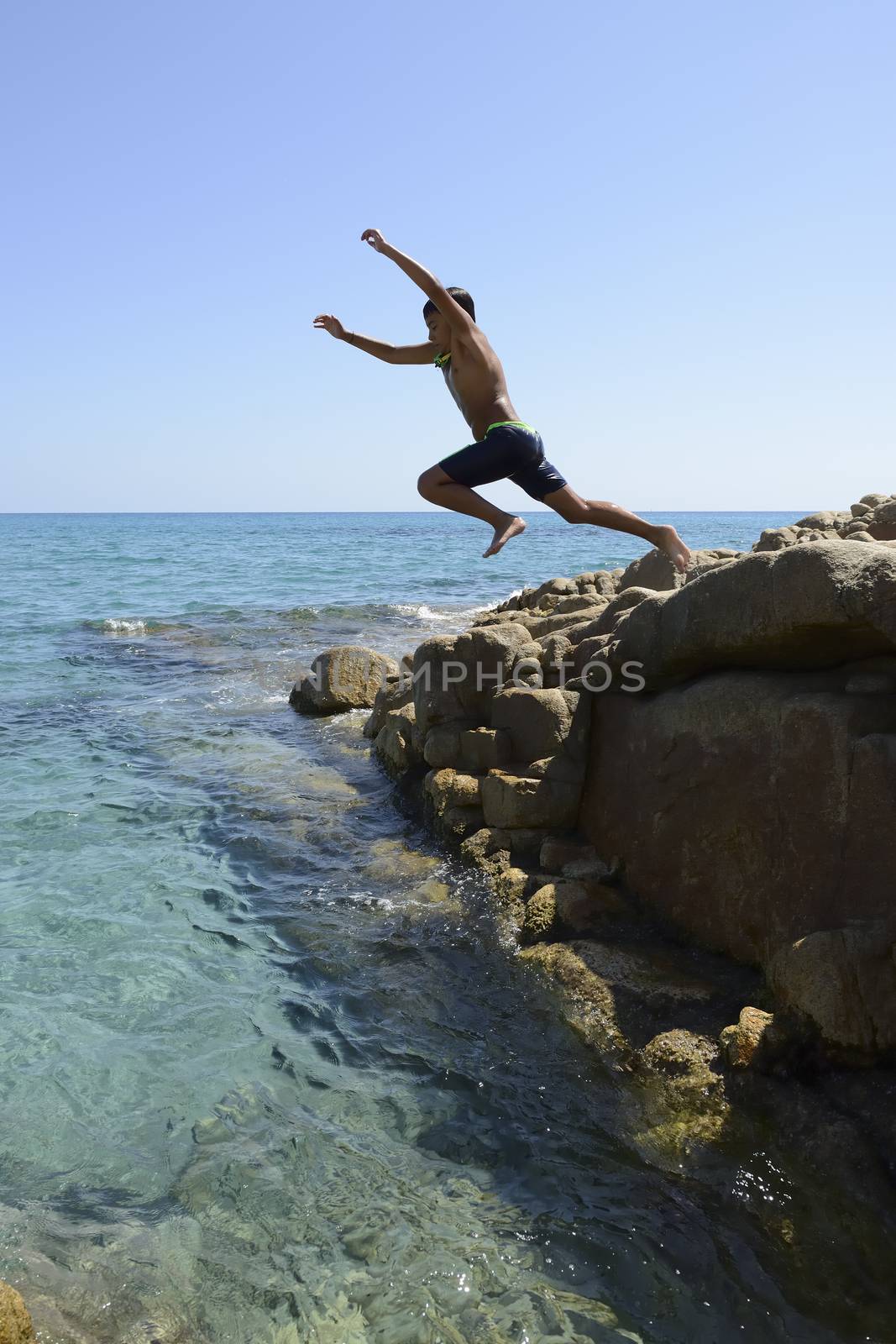 Carefree summer for the boy who dives from the rocks into the sea.