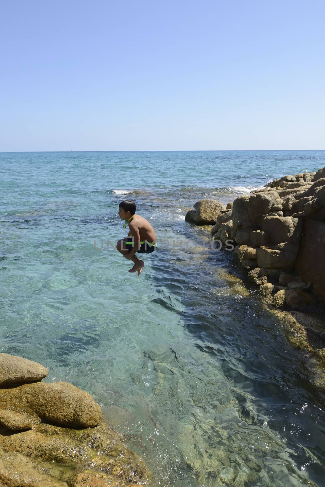 Carefree summer for the boy who dives from the rocks into the sea.