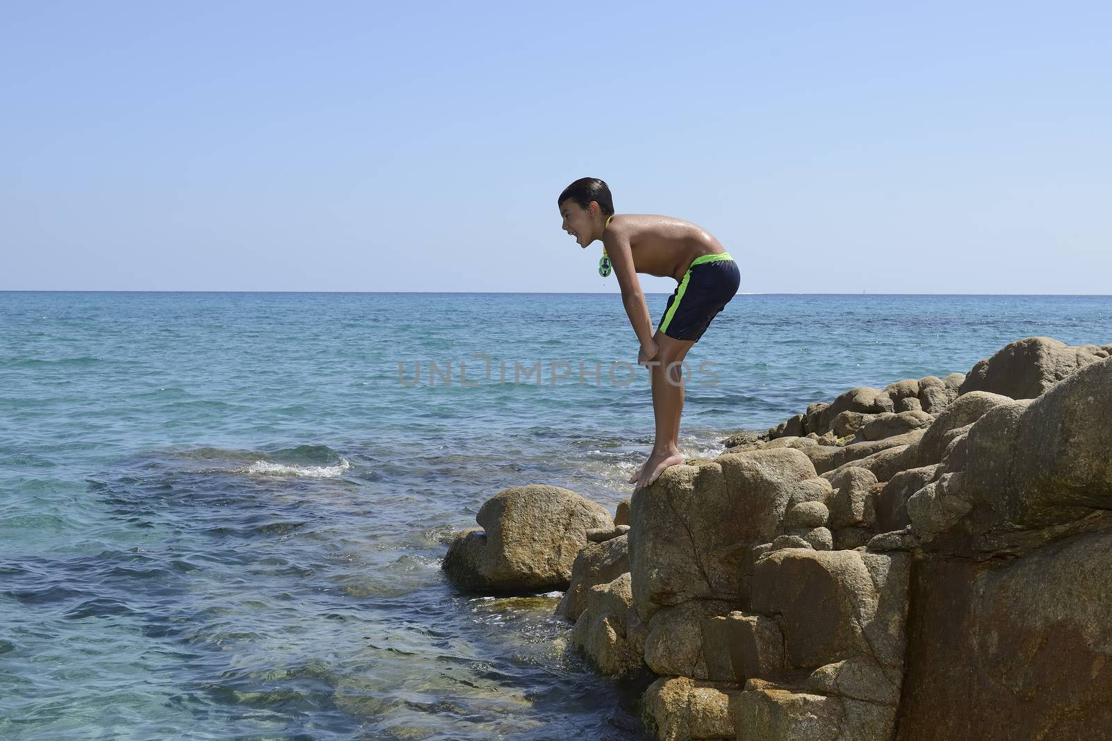 Carefree summer for the boy who dives from the rocks into the sea.