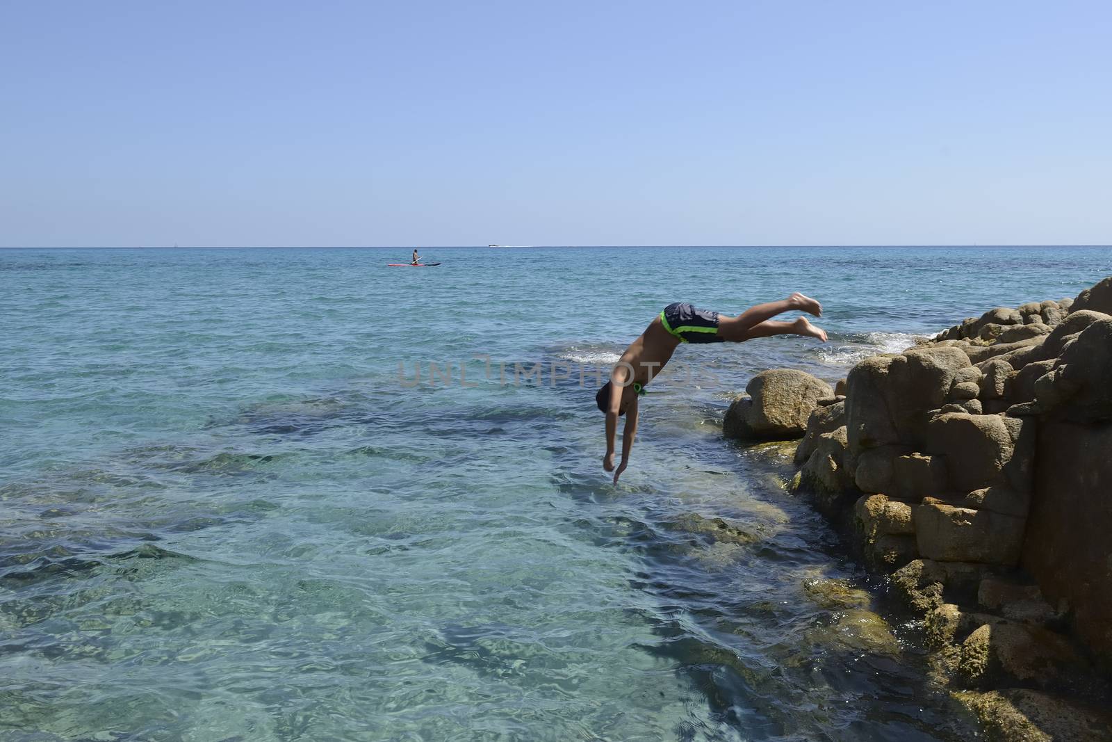 Carefree summer for the boy who dives from the rocks into the sea.