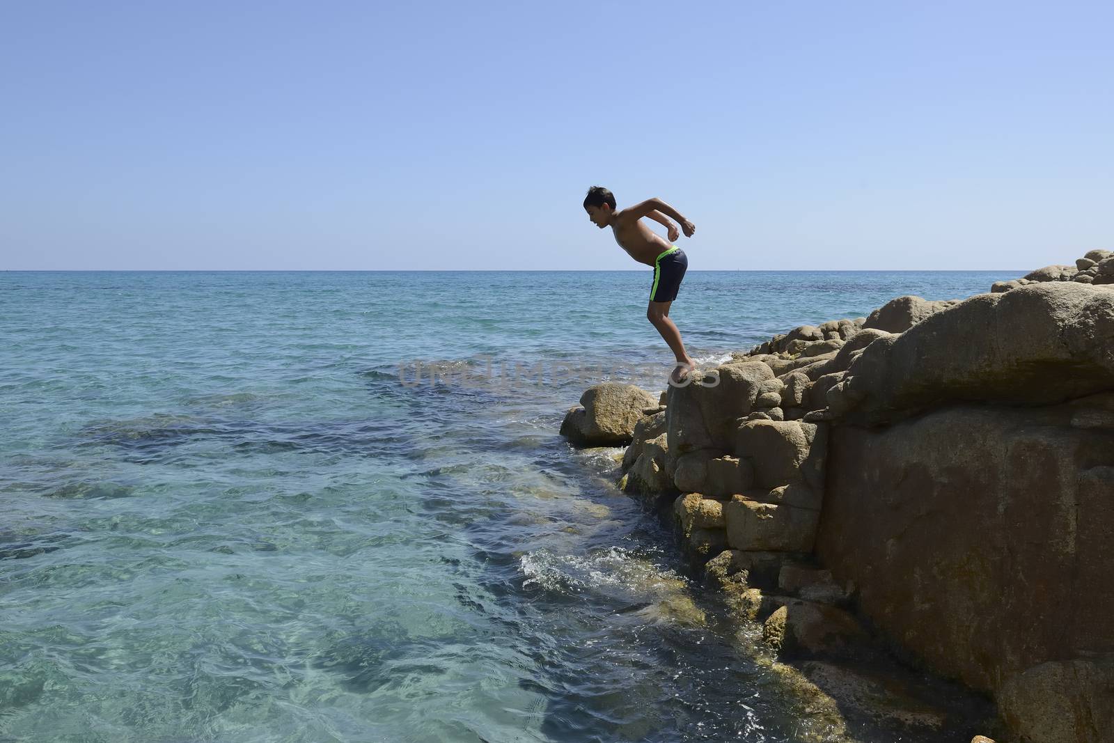 Carefree summer for the boy who dives from the rocks into the sea.