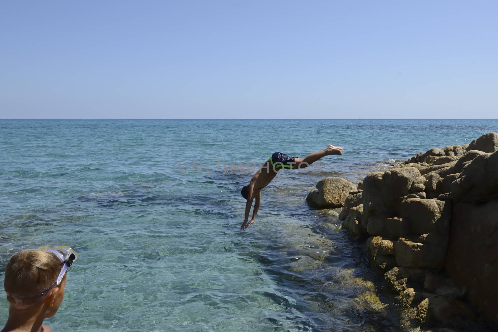Carefree summer for the boy who dives from the rocks into the sea.