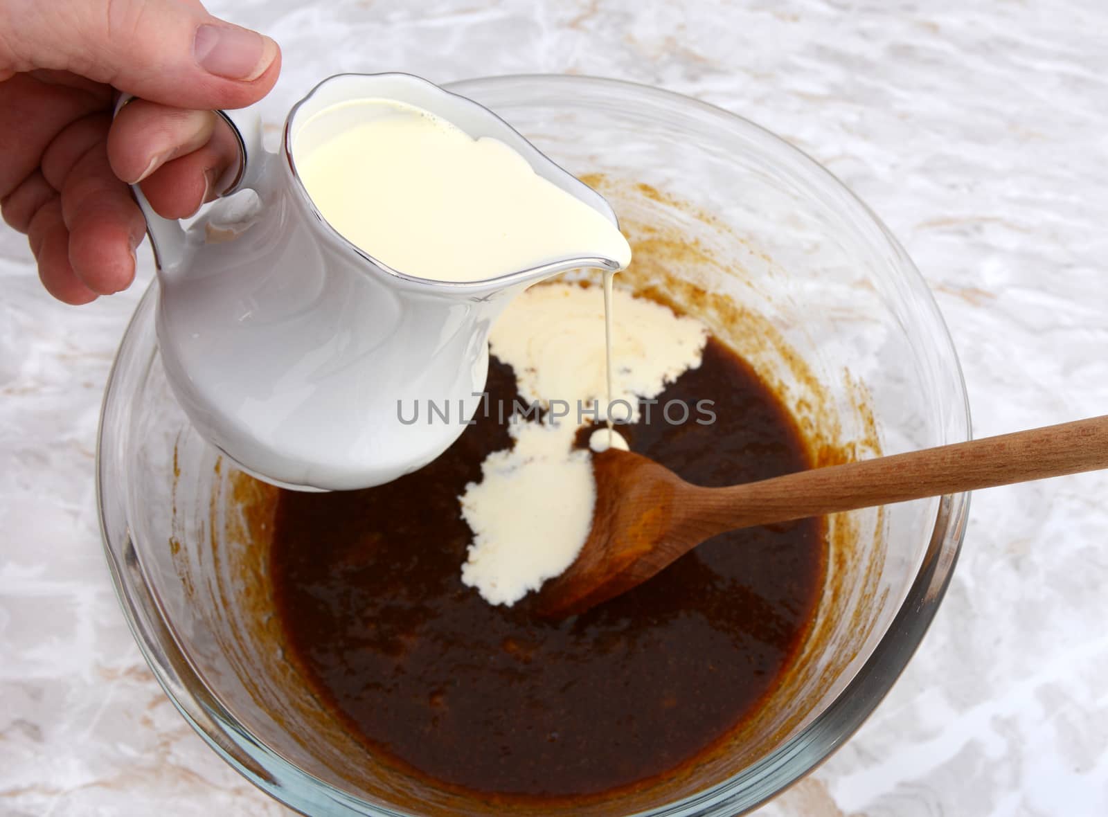 Pouring heavy cream from a jug into pumpkin pie filling in a bowl