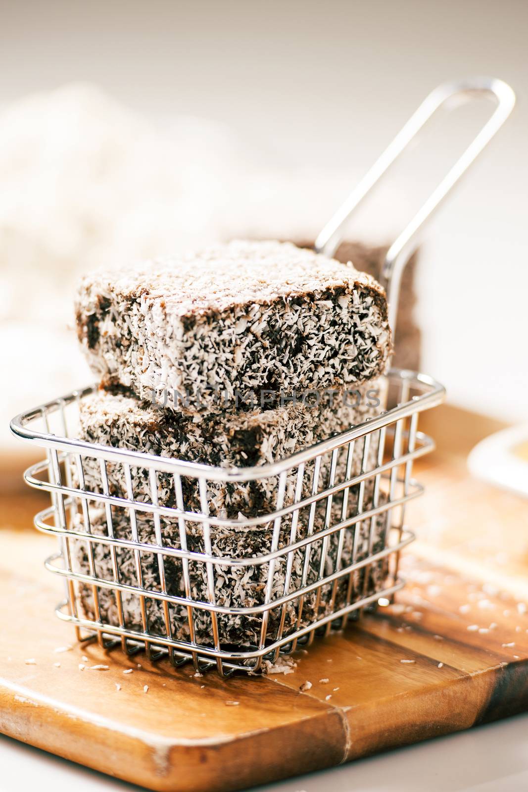 Group of Lamingtons on a timber metal baking tray with food ingredients in the background
