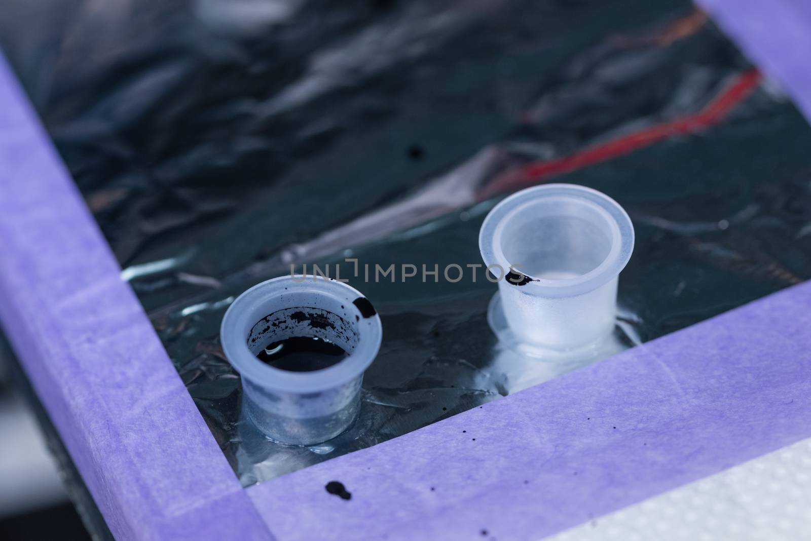 A couple of used tattoo ink cups on a work table.