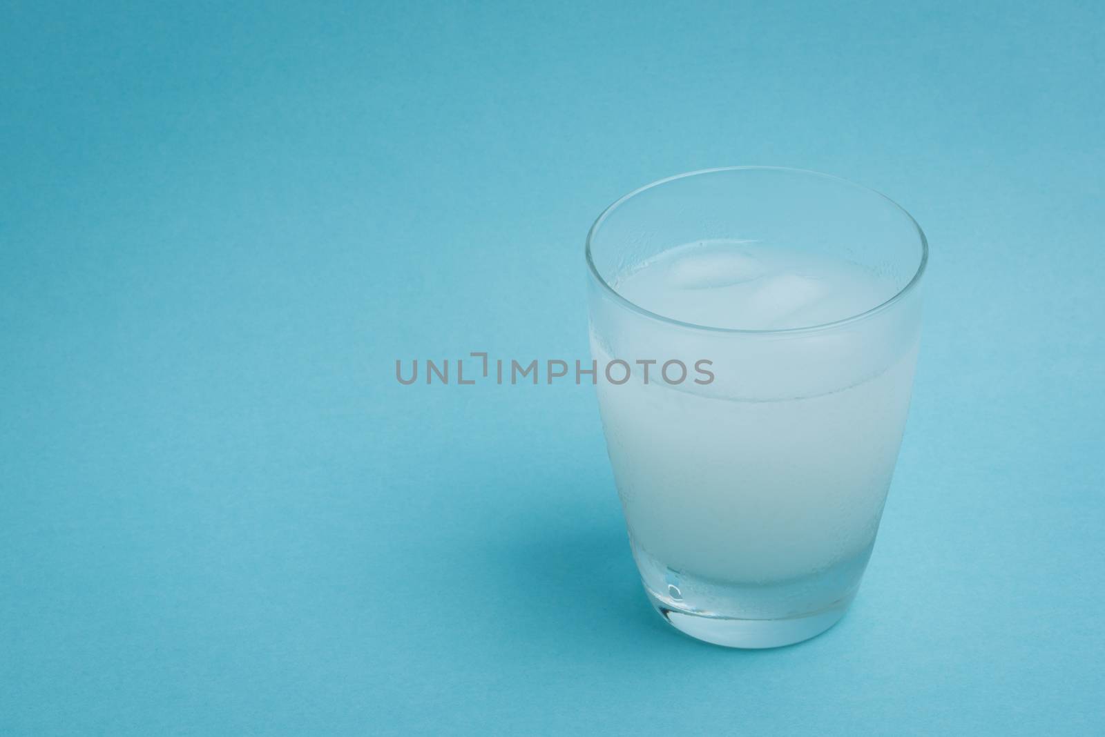 A white iced drink in a glass on a light blue background.