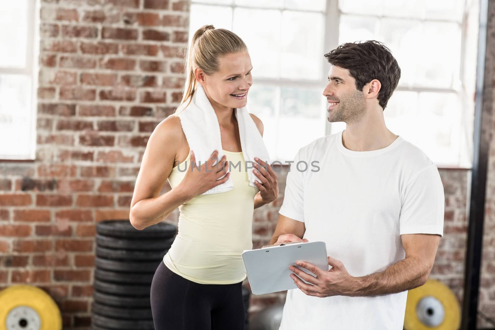 Woman discussing her performance on clipboard with trainer by Wavebreakmedia