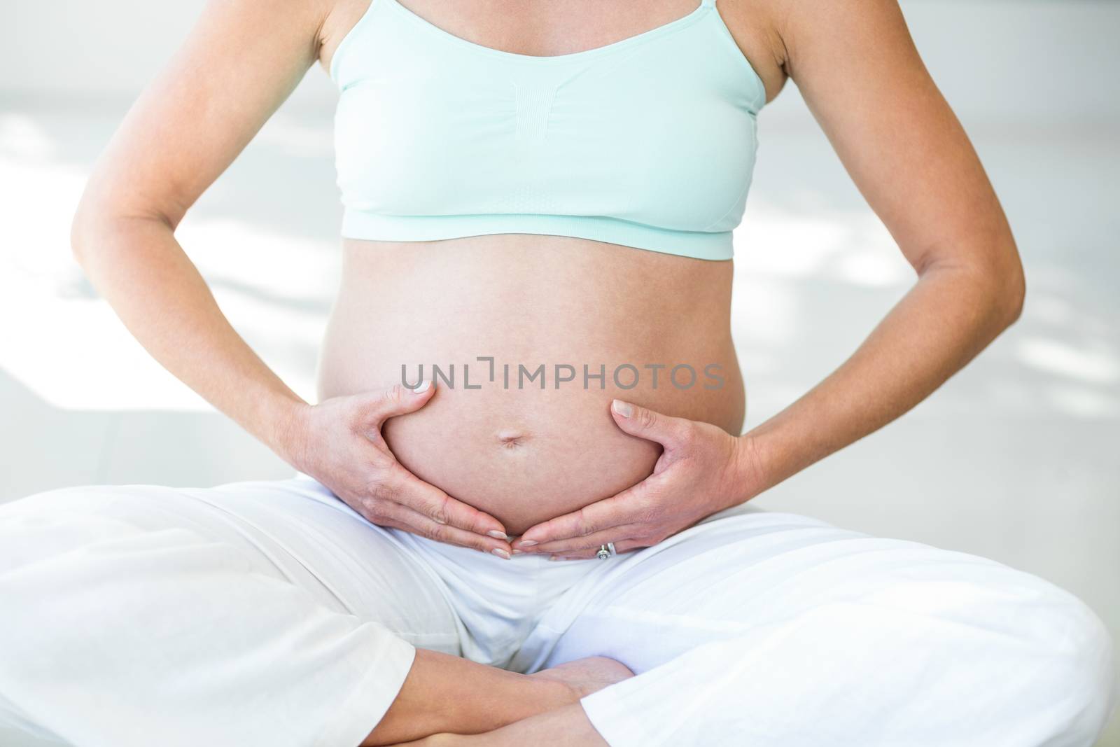 Midsection of pregnant woman doing yoga at home