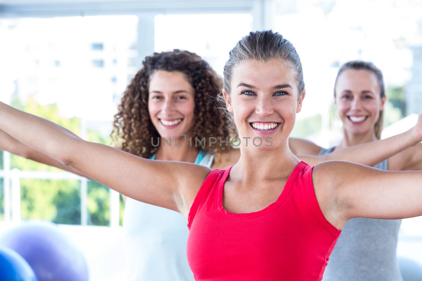 Portrait of cheerful women with arms outstretched in fitness studio