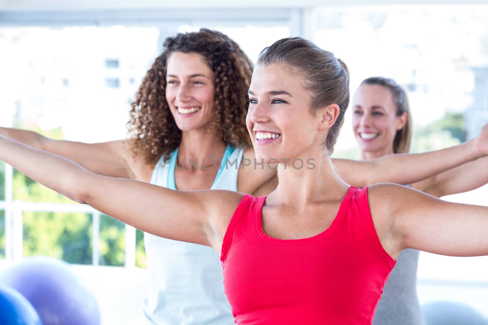 Cheerful women with arms outstretched in fitness studio