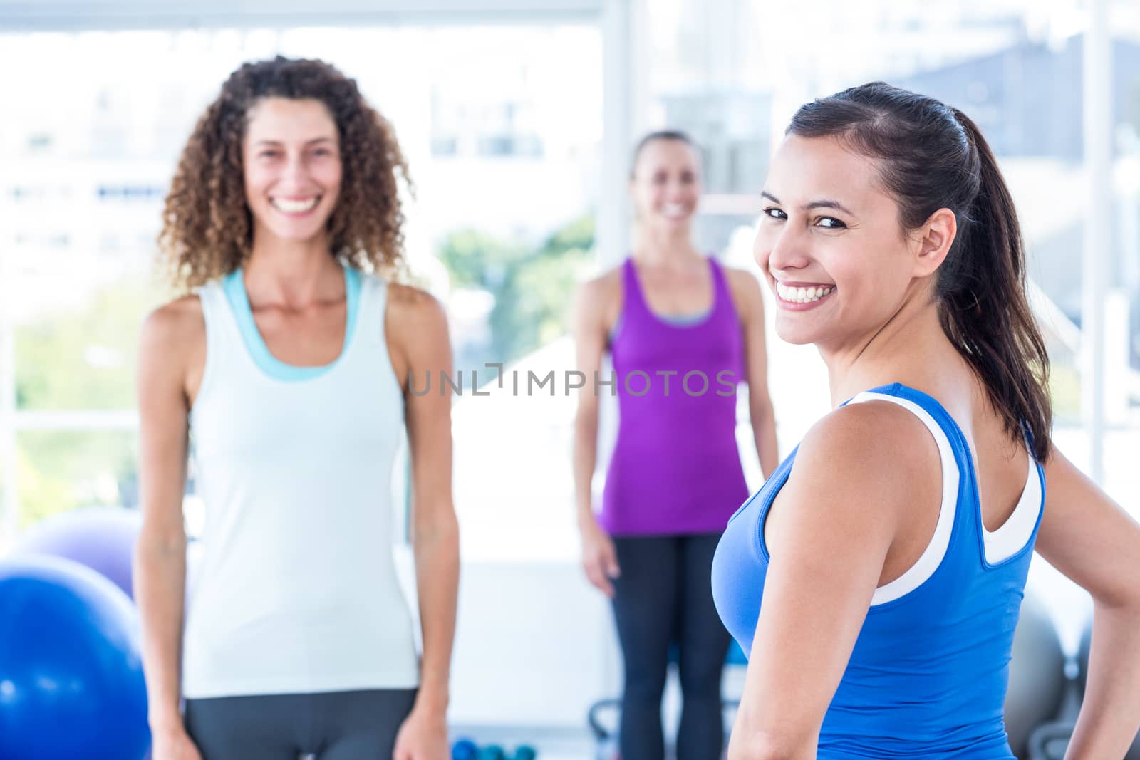 Portrait of cheerful woman with friends at fitness center while standing