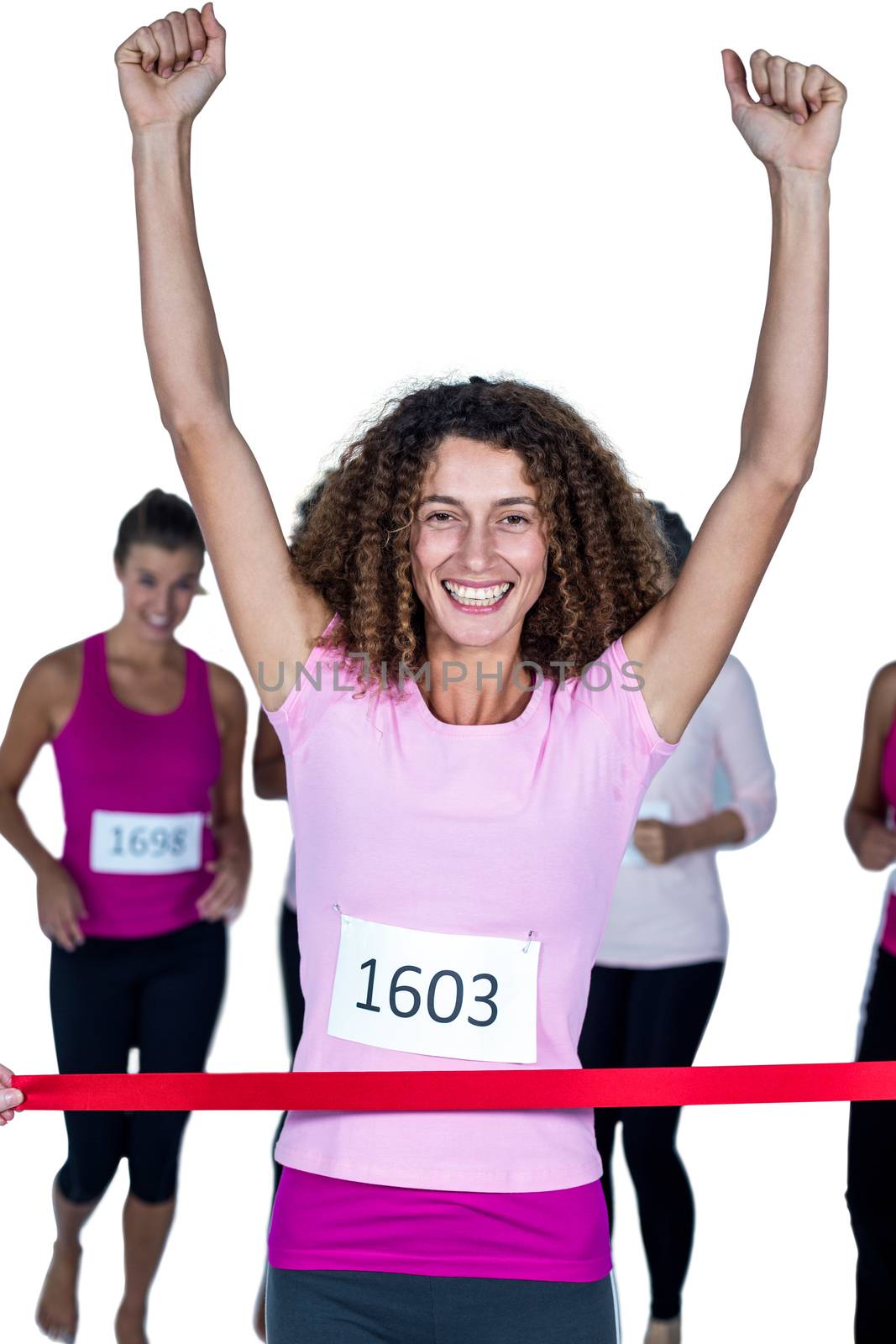 Portrait of smiling winner female athlete crossing finish line with arms raised against white background
