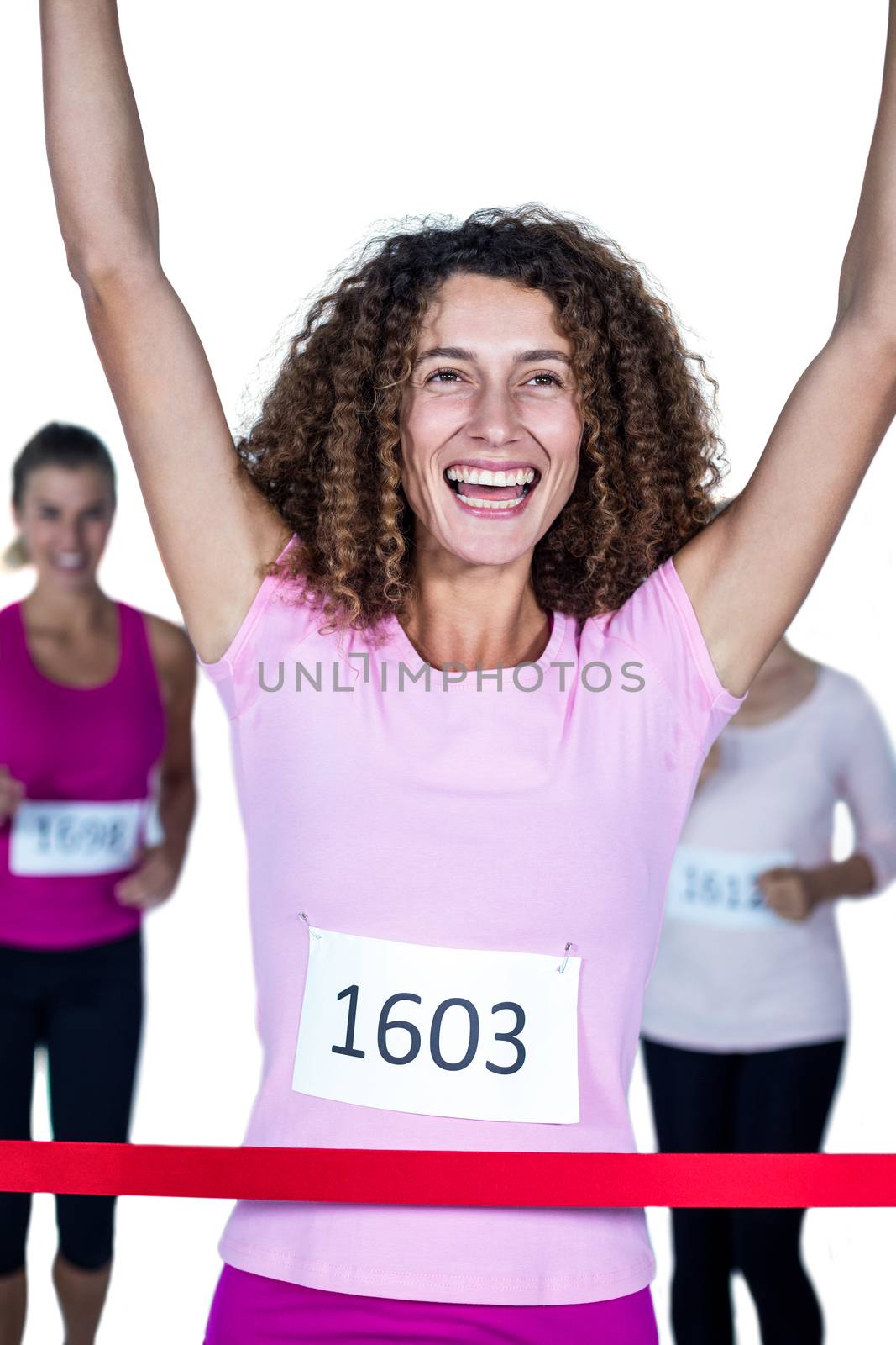 Smiling winner female athlete crossing finish line with arms raised  by Wavebreakmedia