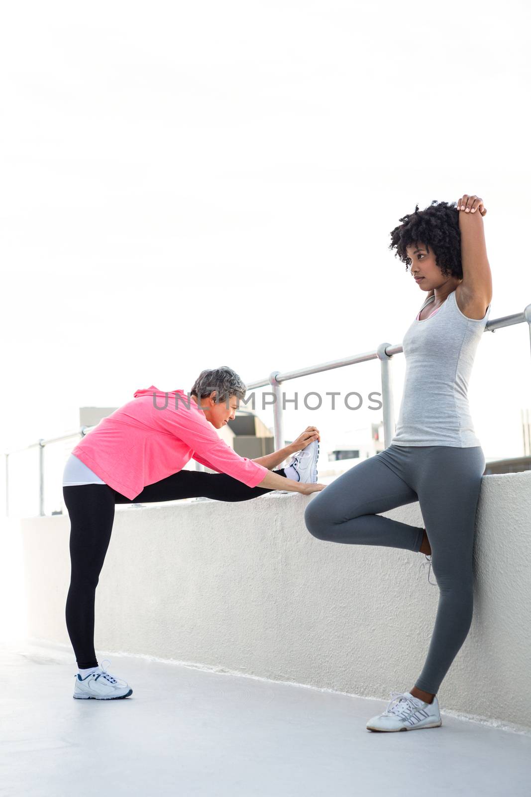 Full length of women stretching by railing