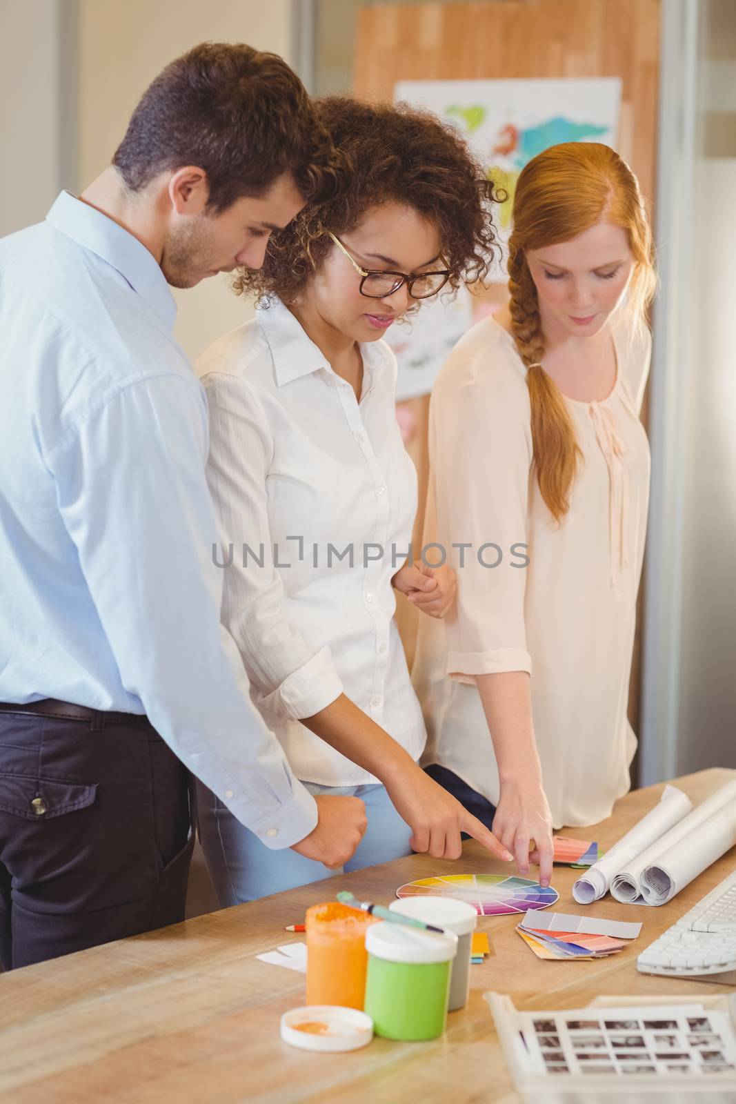 Business people with color samples standing by desk in ofice