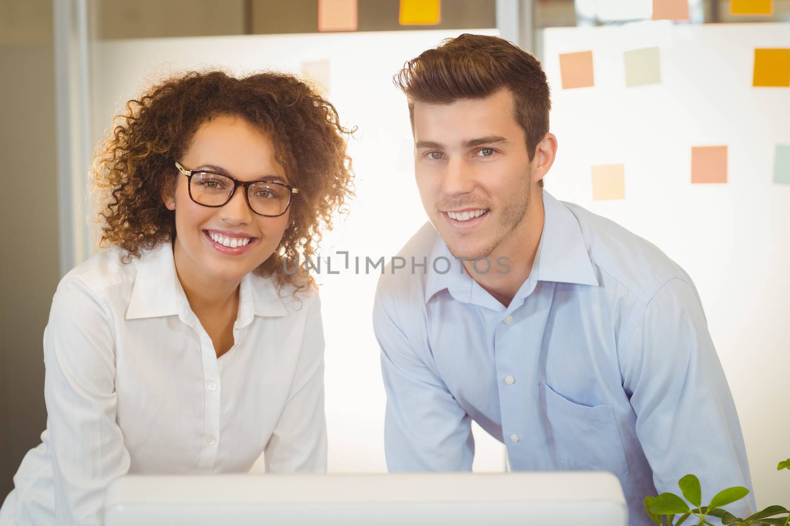 Portrait of business people standing by table in office