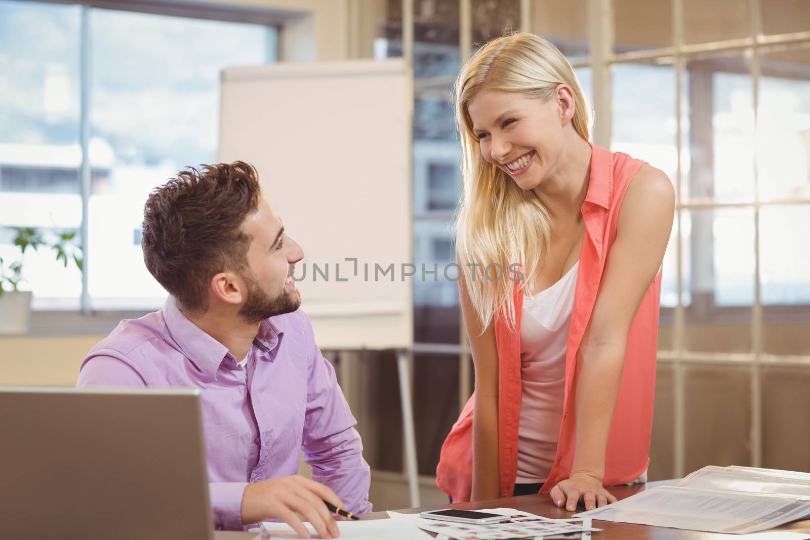 Happy business people talking to eachother by desk desk in creative office