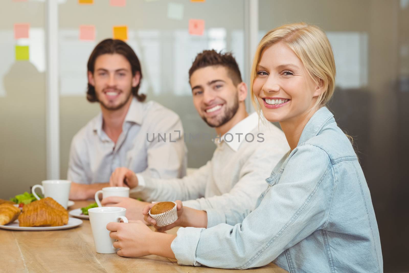 Portrait of business people having snack in canteen at creative office