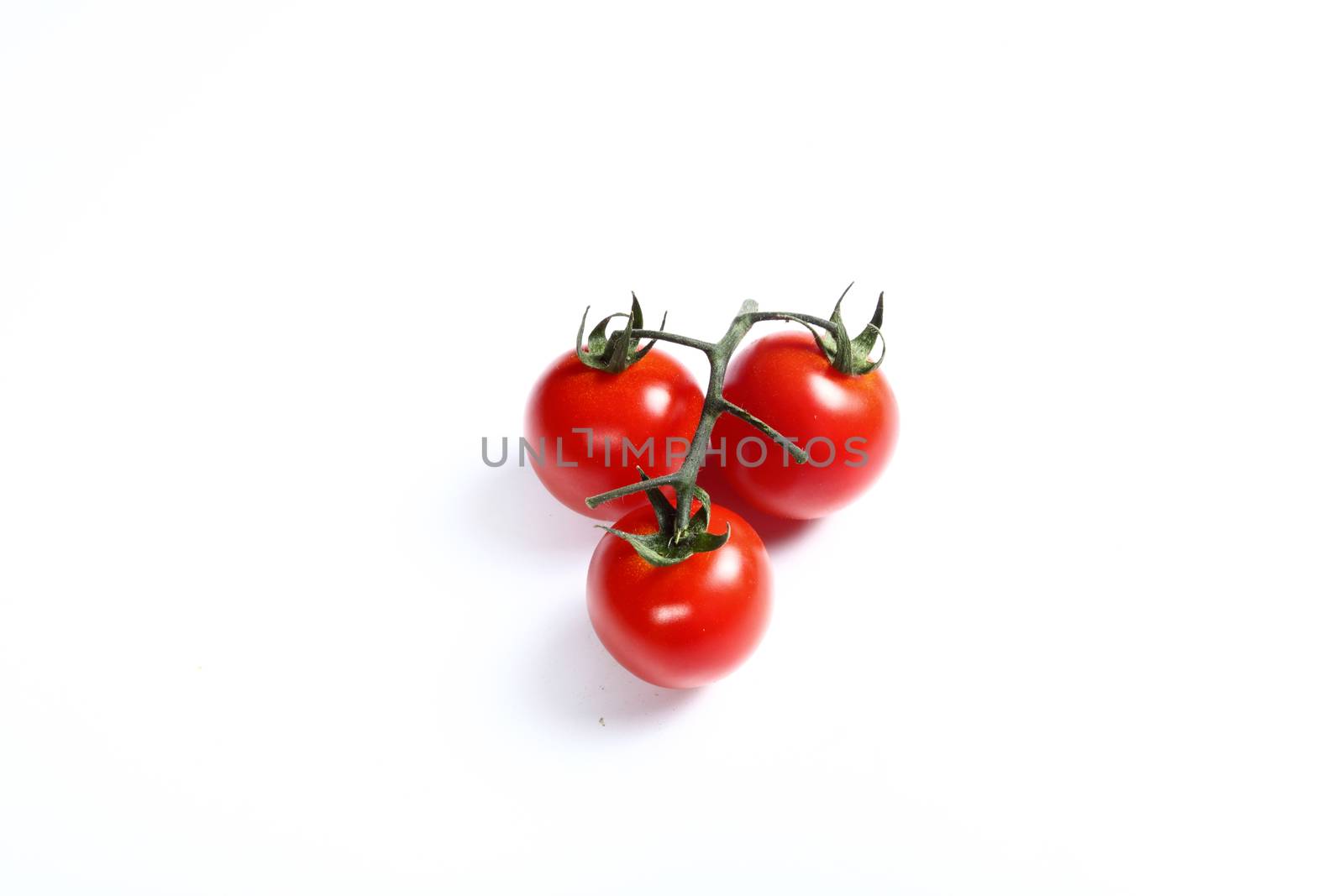 three small tomatoes on white by diecidodici