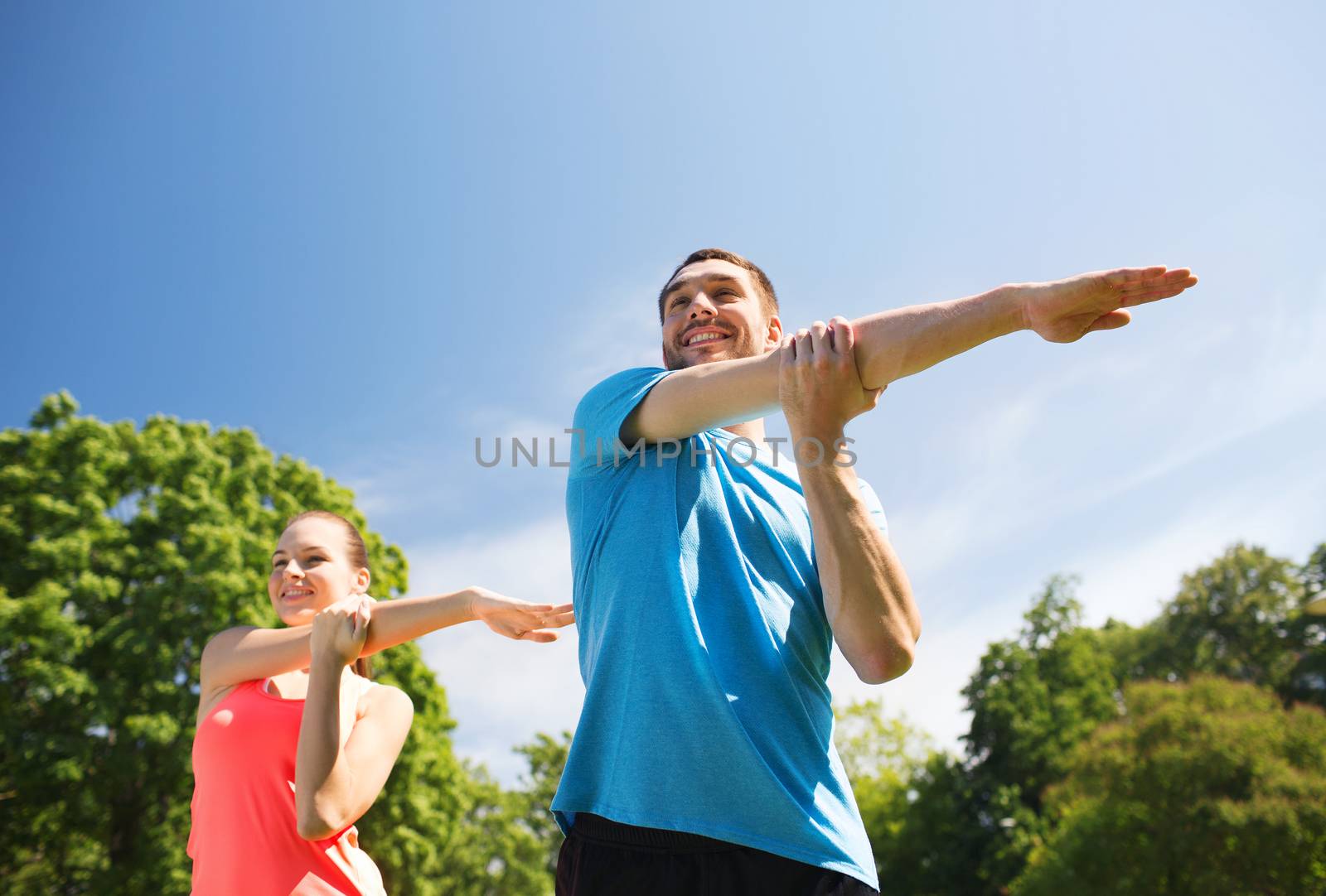 smiling couple stretching outdoors by dolgachov