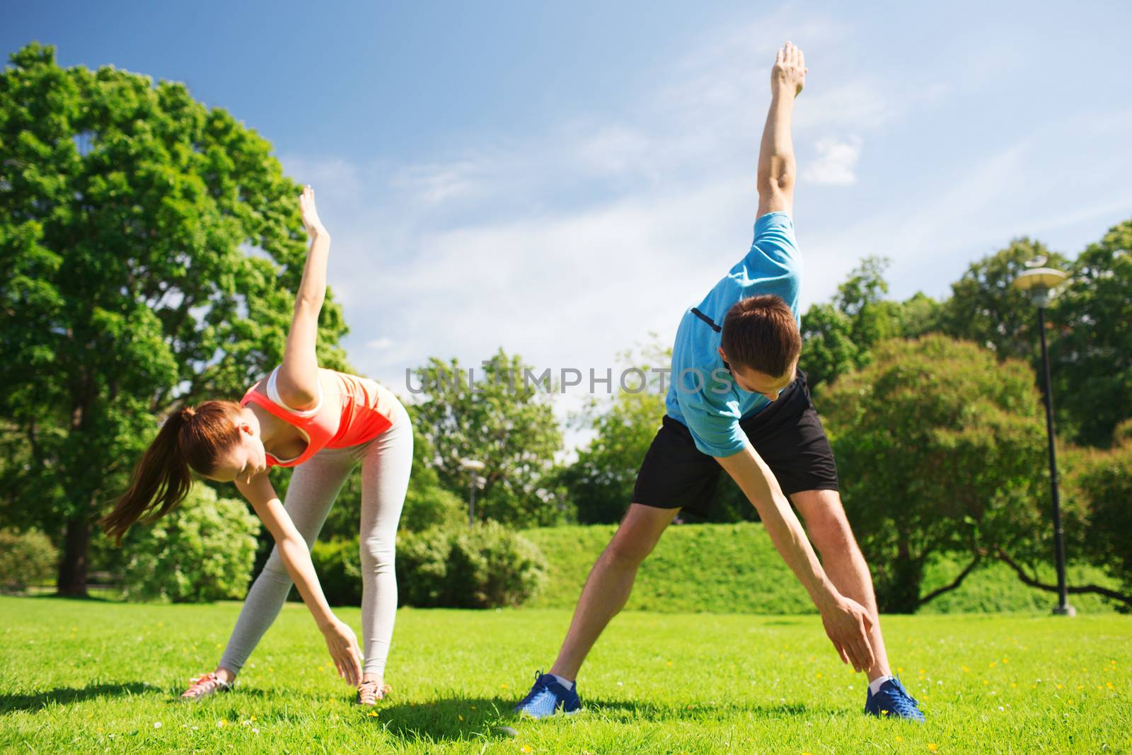 smiling couple stretching outdoors by dolgachov