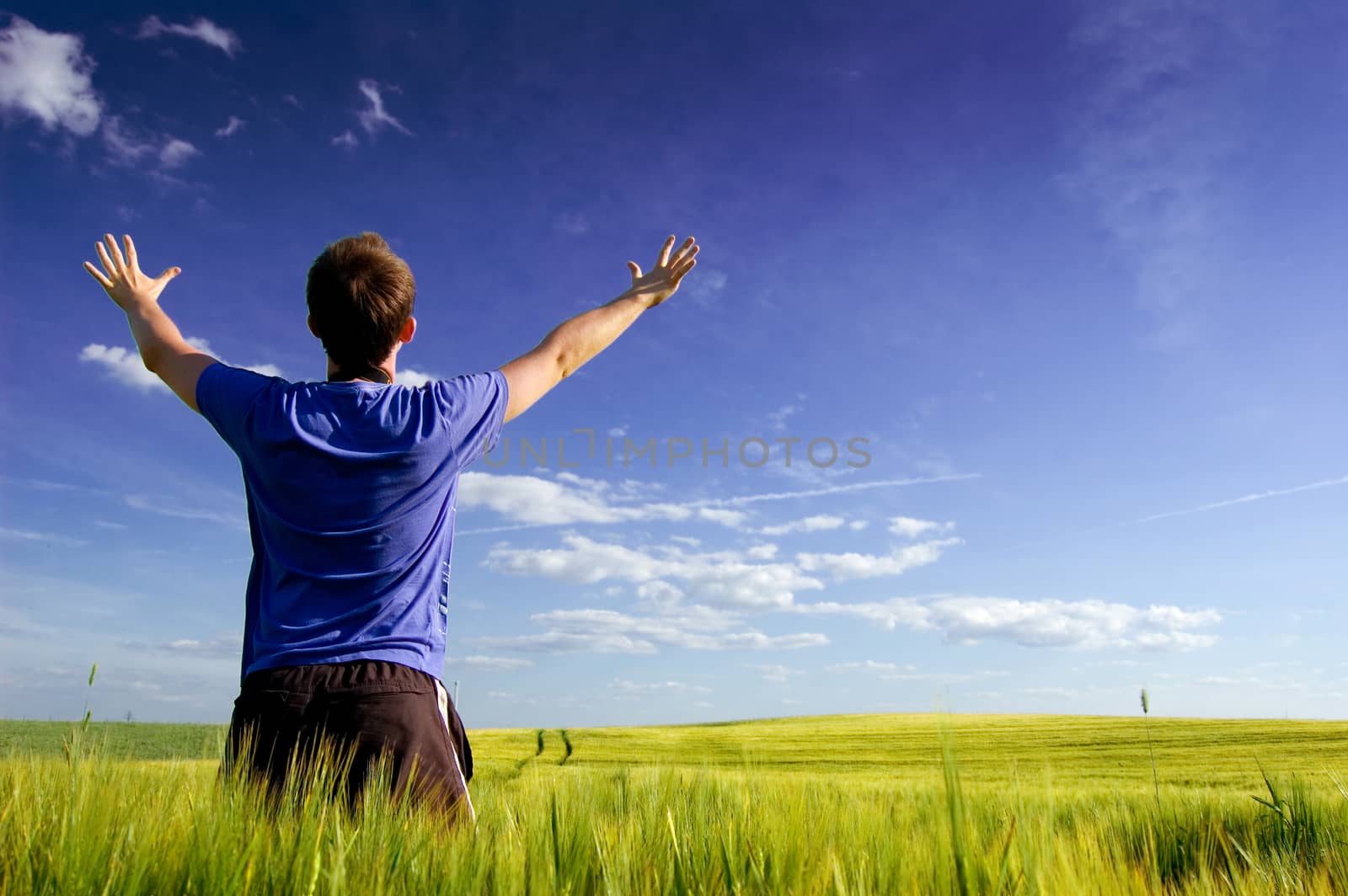 Man standing on the green field at summer and feel the freedom.