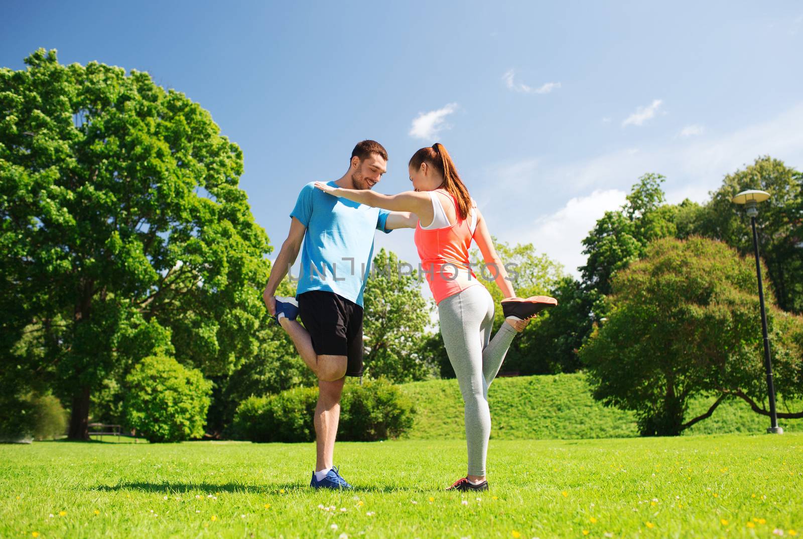 fitness, sport, training and lifestyle concept - smiling couple stretching outdoors